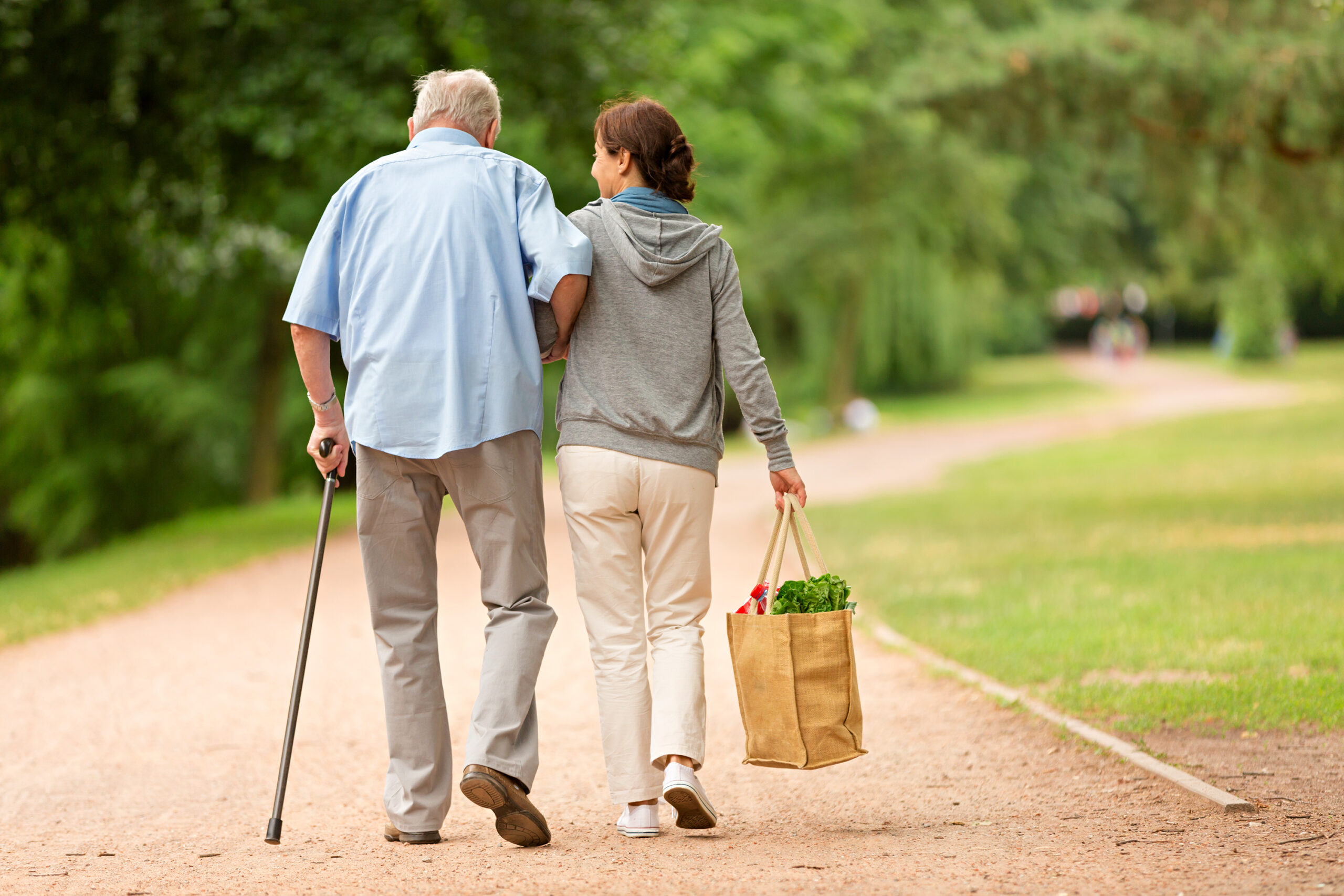 a woman holding hands with senior and walking in the garden